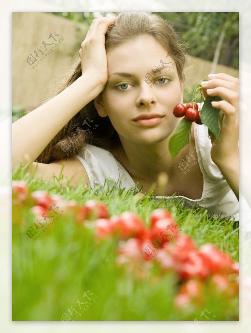 爬在草丛中手拿浆果的漂亮性感女孩图片