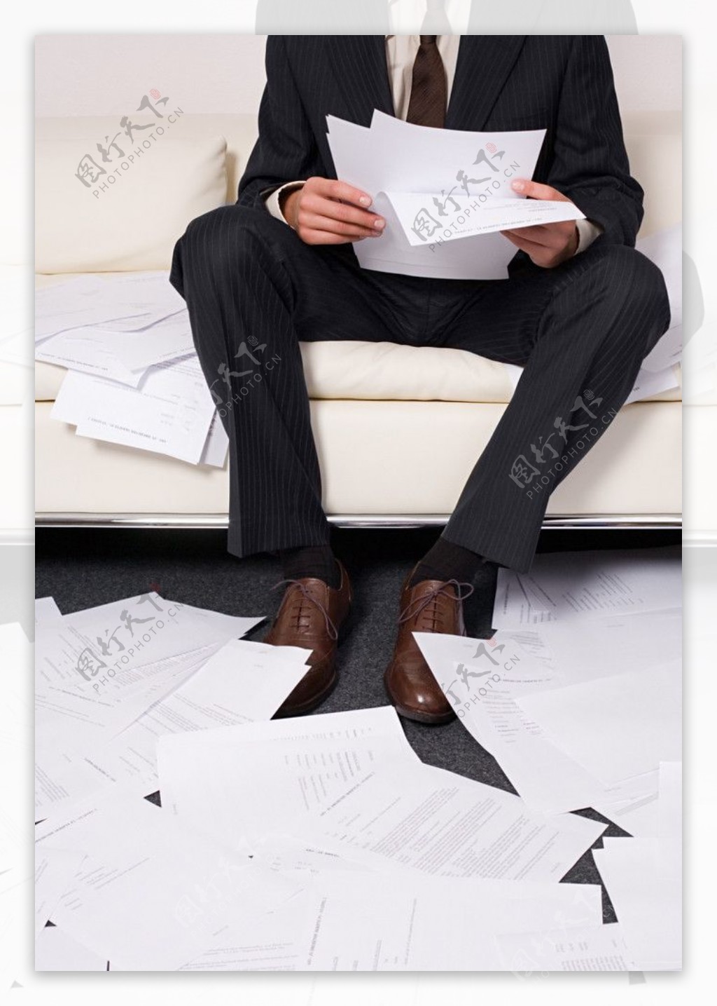 坐在沙发上看文件的商务人物特写满地的文件图片