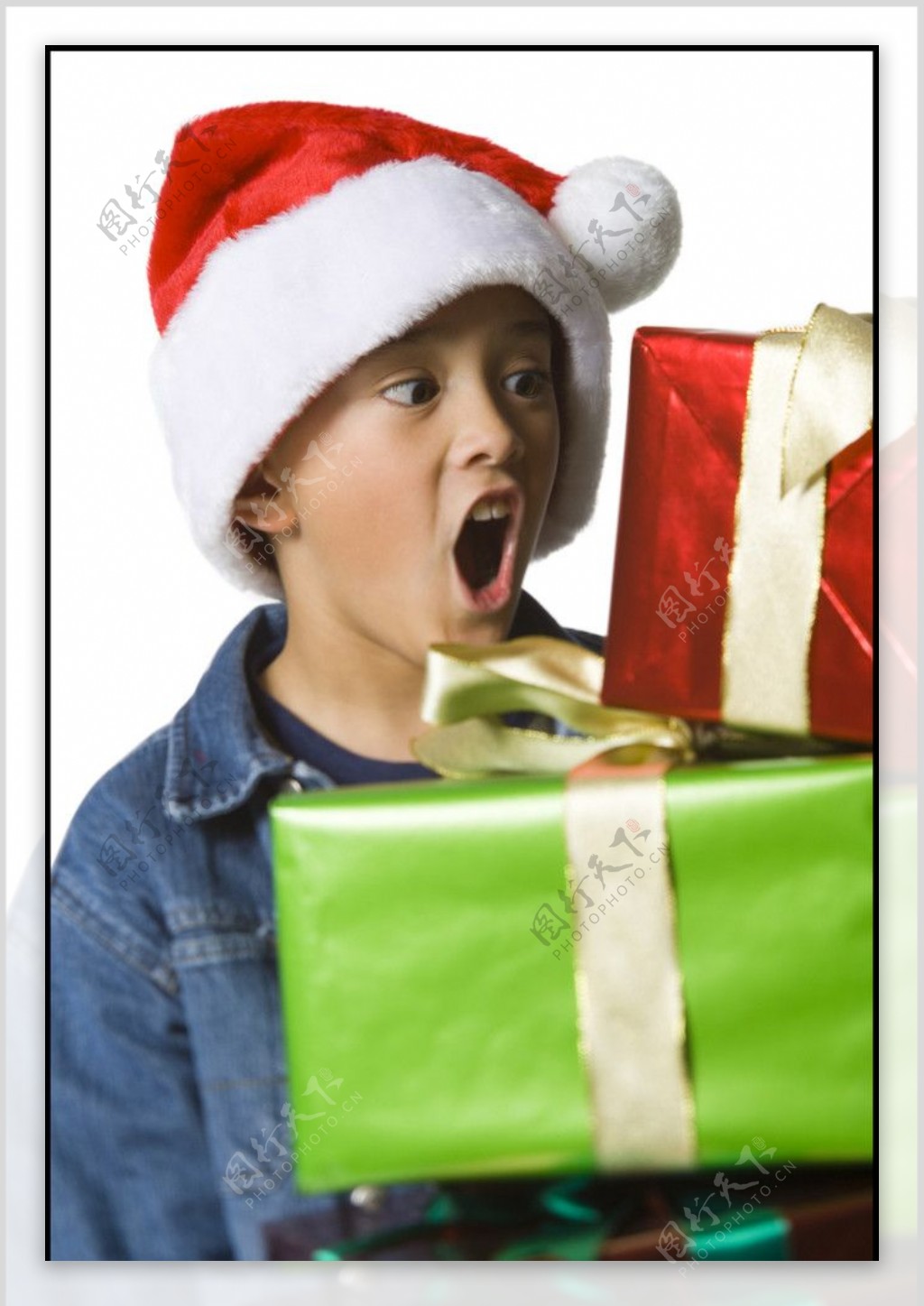 带圣诞帽冲着礼盒呼喊的小男孩图片