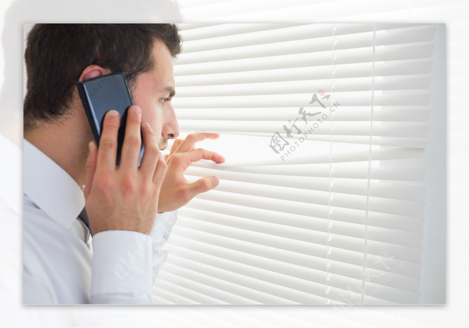 窗户前接电话的职业男性图片