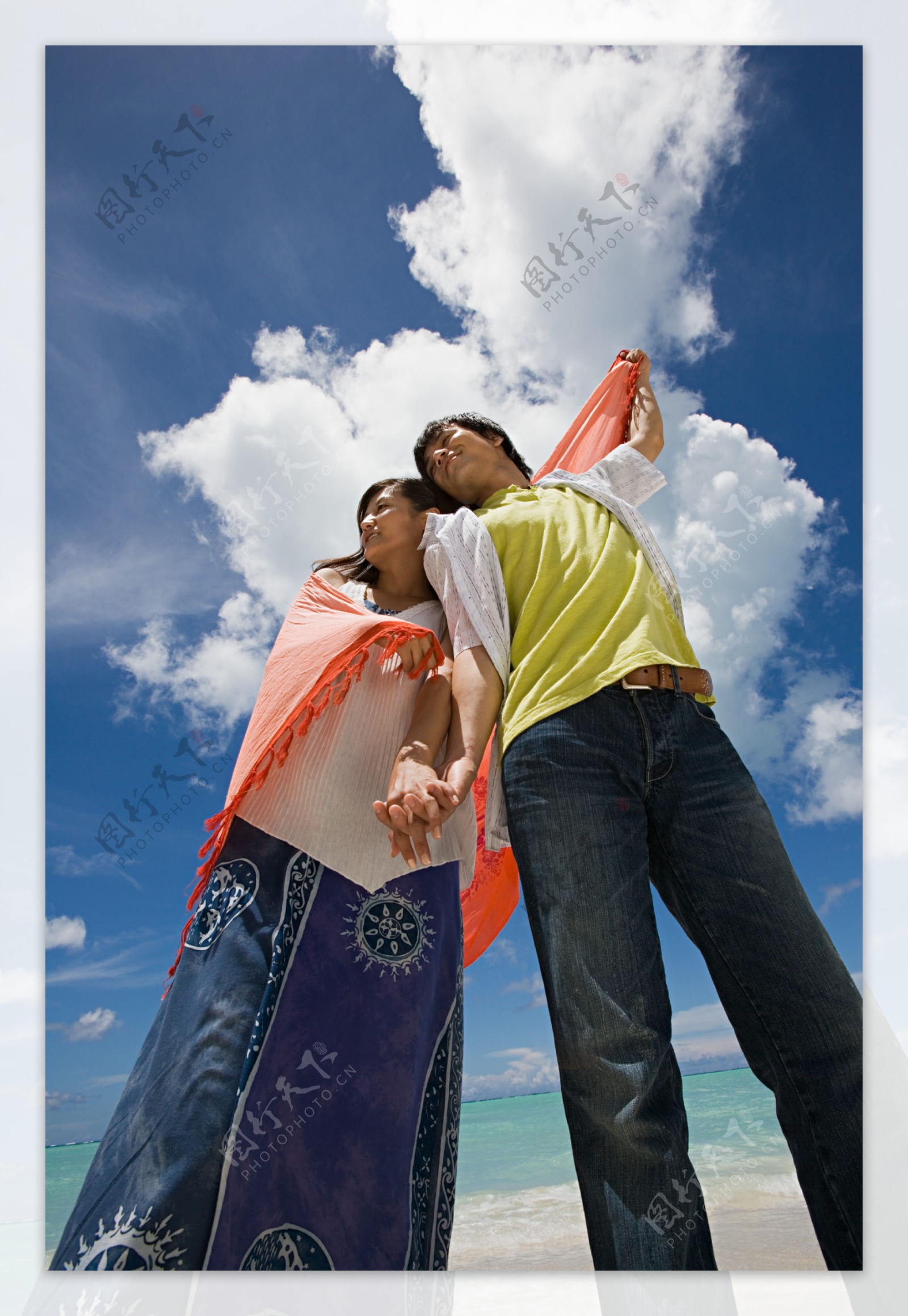 站在海边披着红色围巾的情侣仰视图图片