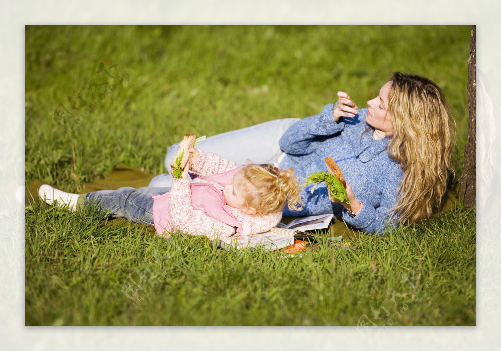 躺在草地上吃东西的母女图片
