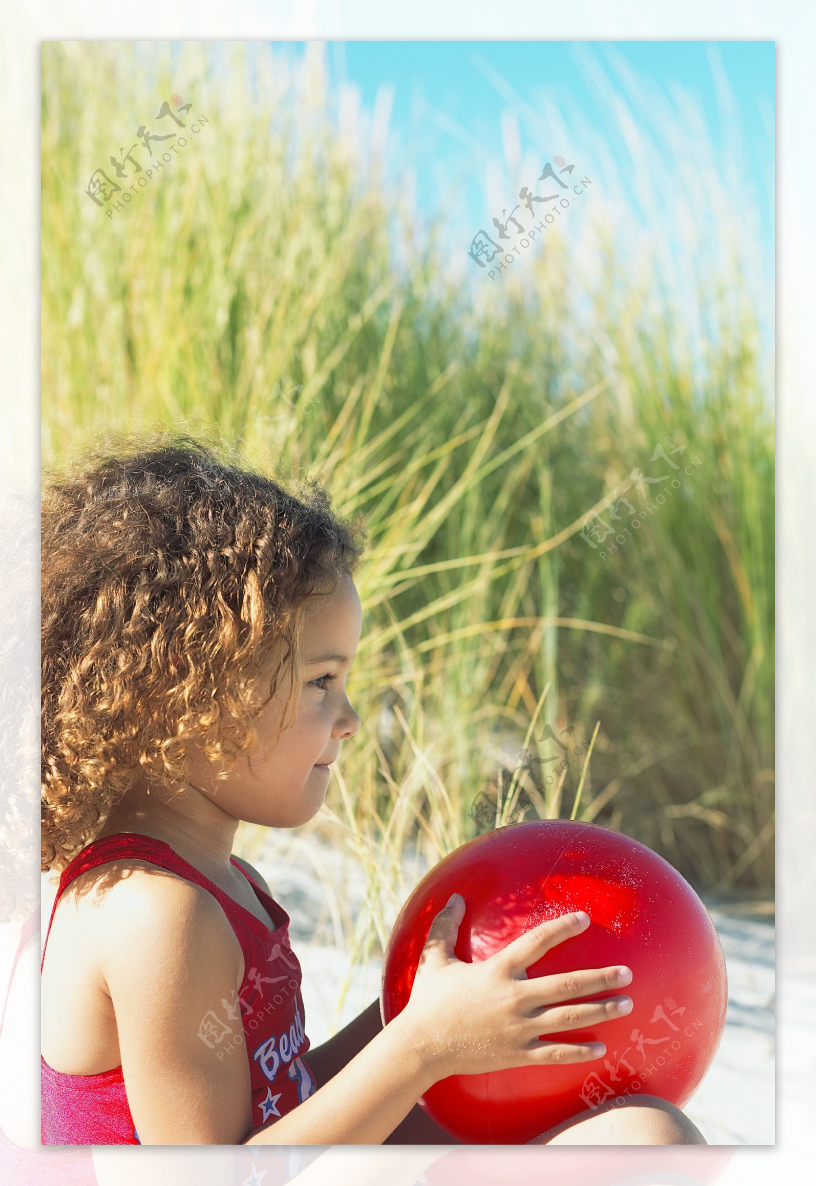 沙滩上手拿球的小女孩图片
