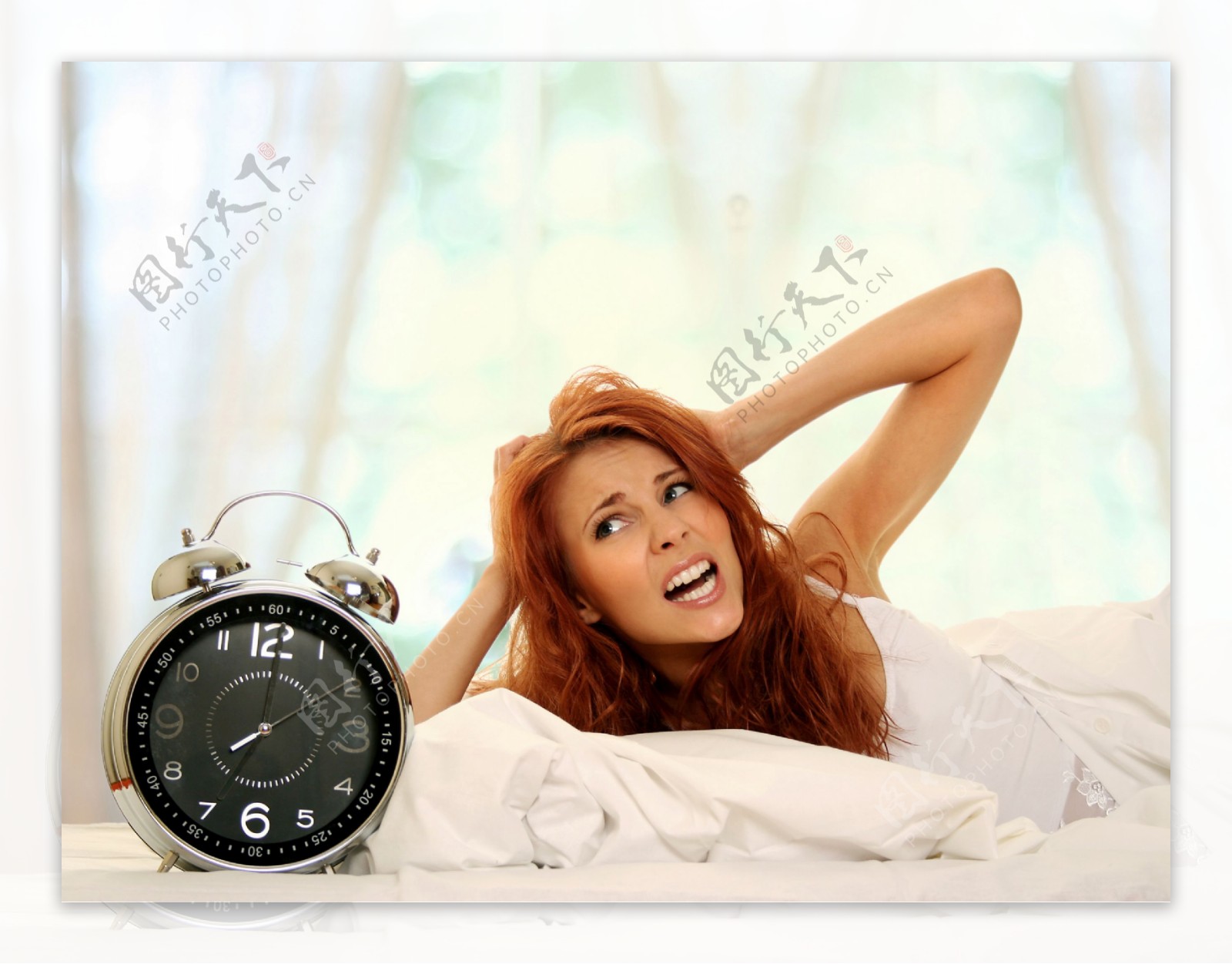 躺在床上抓头发的女人与闹钟图片