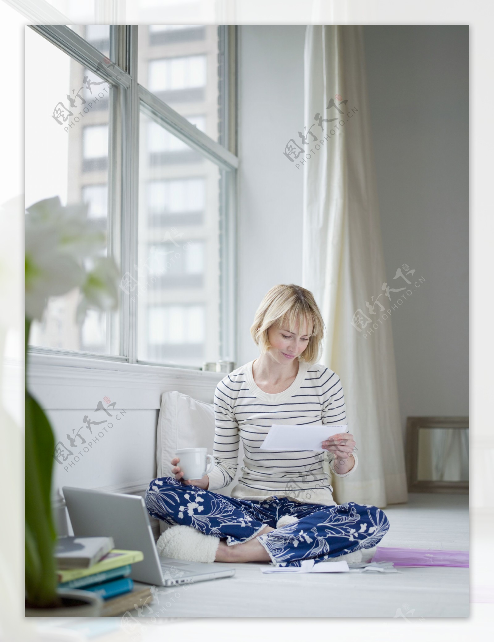 电脑旁坐在地上端着茶杯的女人图片